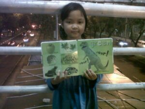 An Indonesian girl poses with her drawings