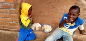 Two Malawi children enjoying a full meal