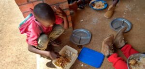 Hungry Malawi children enjoying a full meal