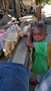 A young child in Tanzania poses with food items