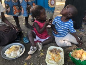 Two kids sitting down and having rice