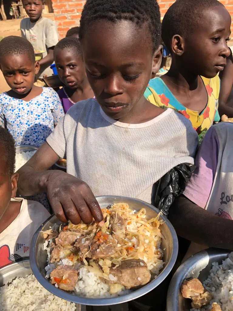 A boy holding food plate and having food