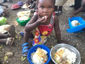 A small girl sitting and eating rice
