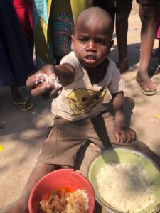 A boy is showing his food plate to the camera