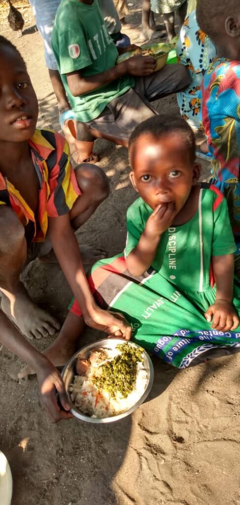 Child wearing green dress eating with fingers